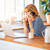 Woman on phone looking at a laptop in her kitchen